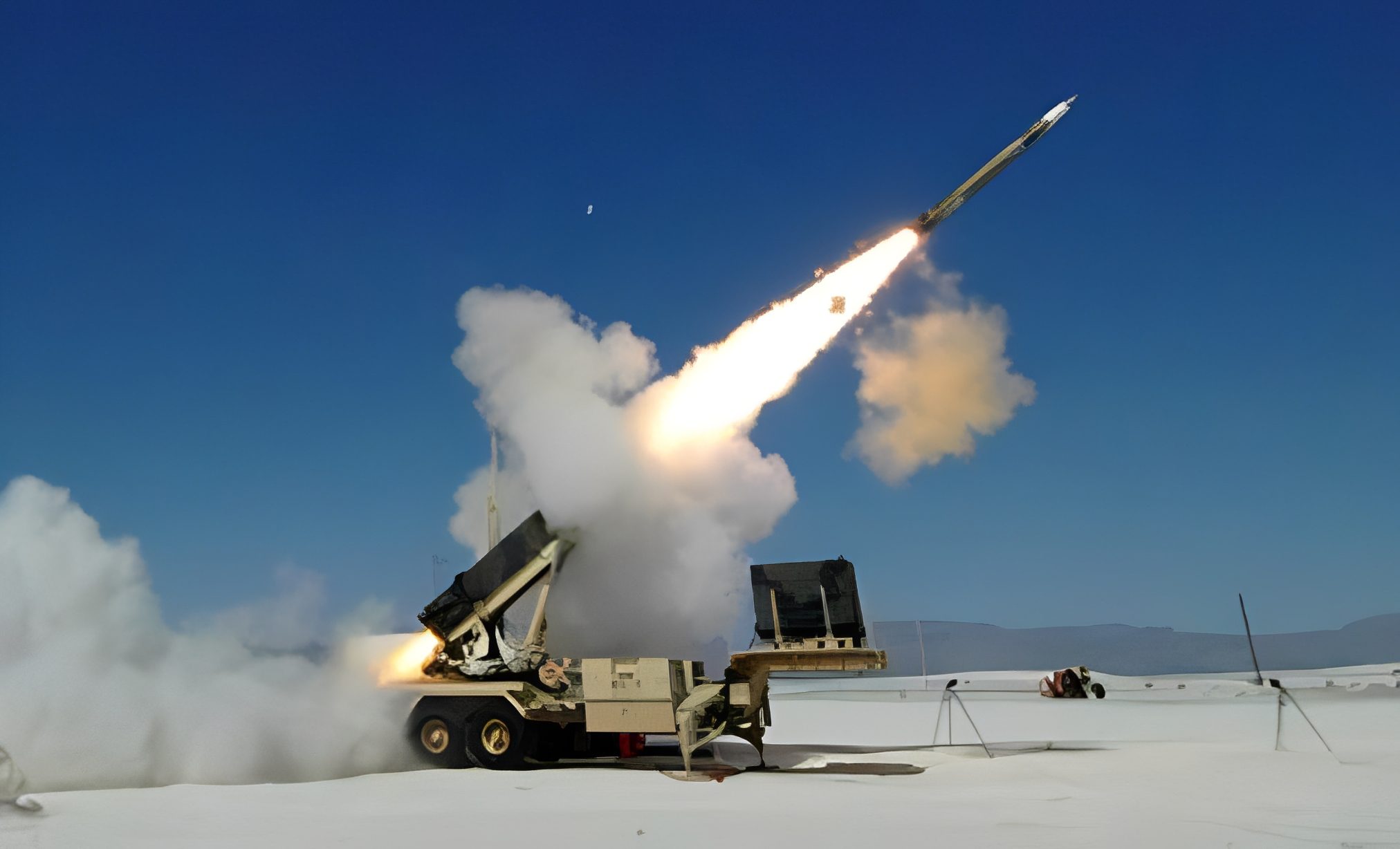 Missile launching from military vehicle, clear sky.